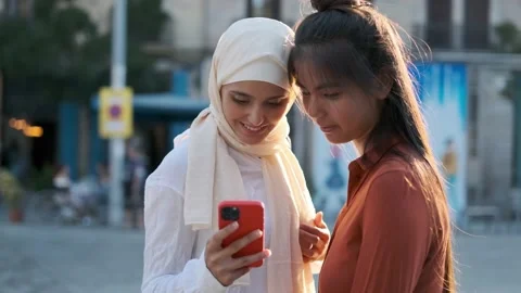 Multi-ethnic female friends looking at something on the mobile phone while Stock Footage 218356293