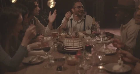 Multi-ethnic friends eating gourmet birthday cake at rustic dinner party Stock Footage