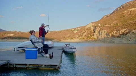 Multi-ethnic friends getting ready to fish on pier by lake Stockbeeldmateriaal 230426423