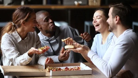 Multi ethnic friends spending time together chatting laughing eating pizza Stock Footage