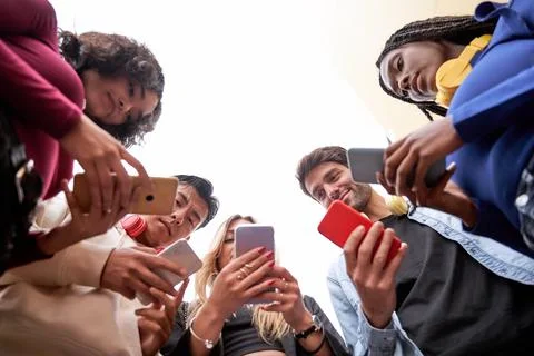 Multi-ethnic friends using their mobile phones while standing in a circle. 스톡 사진