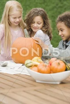 Multi-ethnic girls carving pumpkin Stock Photos