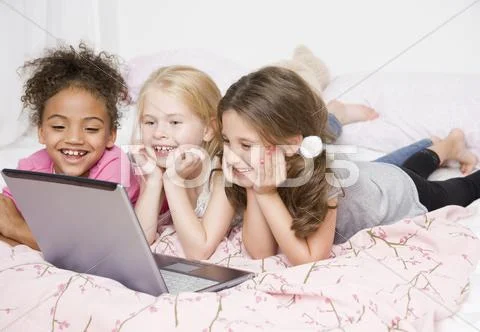 Multi-ethnic girls looking at laptop Stock Photos