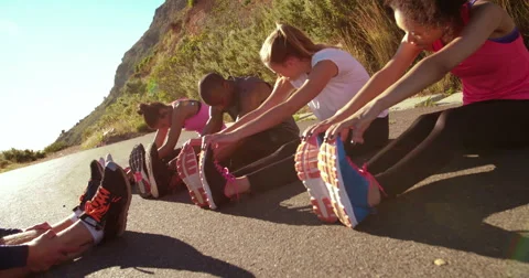 Multi-ethnic group of athletes doing hamstring stretch exercise outside Stock Footage 61404025