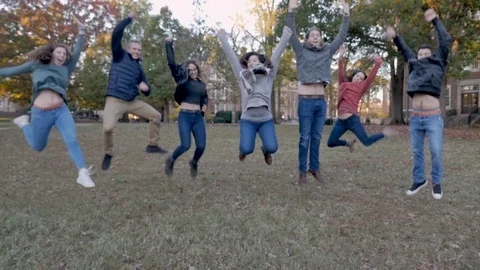 Multi ethnic group of college students jumping and giving high fives on campus Video stock 104364741