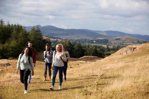 Multi ethnic group of five happy young adult friends walking on a rural path Stock Photos
