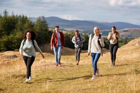 Multi ethnic group of five happy young adult friends walking on a rural path Stock Photos