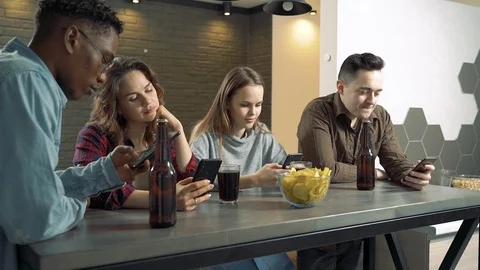 Multi-ethnic group of friends actively using phones at a bar or at home Stock Footage 122736658