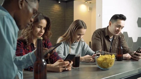Multi-ethnic group of friends actively using phones at a bar or at home Stock Footage 122738790