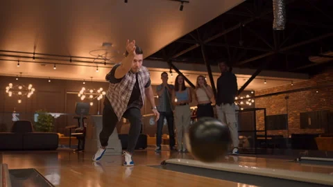 Multi ethnic Group of friends in a bowling club Caucasian man throws a ball and Stock Footage 168230356