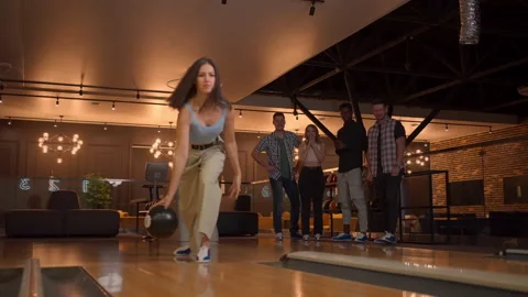 Multi ethnic Group of friends in a bowling club a woman throws a ball and knocks Stock Footage 168230638