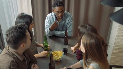 Multi-ethnic group of friends talking laughing and drinking beer at a bar Stock Footage 122690681