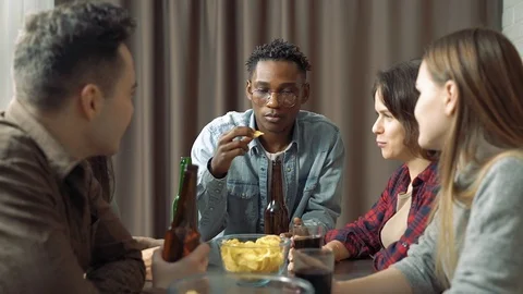 Multi-ethnic group of friends talking and drinking beer at a bar or at home. Stock Footage 122742143
