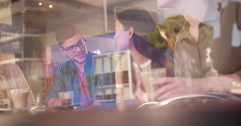 Multi-ethnic group of hipster friends sitting at cafe window Stock Footage