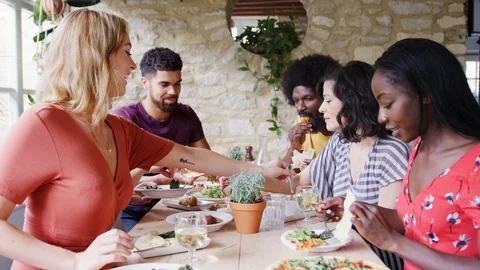 A multi-ethnic group of mixed age adult friends eating lunch together at table Stock Footage