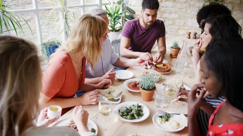 A multi-ethnic group of mixed age adult friends eating tapas together at lunch Stock Footage 99753200