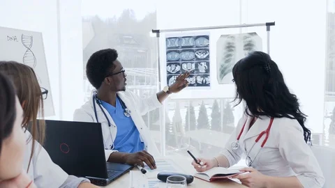 Multi-ethnic group of professional doctors with x-ray of the patient are meeting Stock Footage 105959632