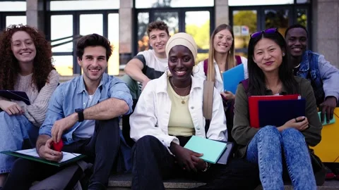 Multi-ethnic group smiling students sitting on stairs holding folders looking at Stock Footage 268236777