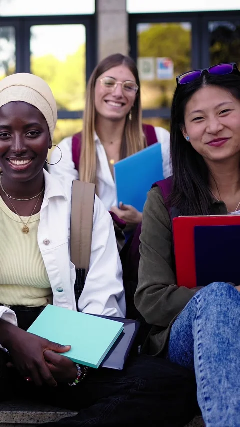 Multi-ethnic group smiling students sitting on stairs holding folders looking at Stock Footage 269241782