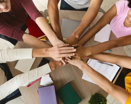 Multi ethnic group of students joining hands together in cooperation Stock Photos
