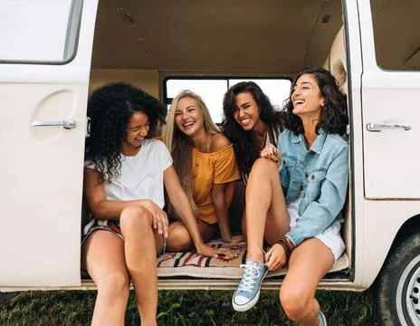 Multi ethnic group of women having fun while sitting in a car. Four friends Stock Photos