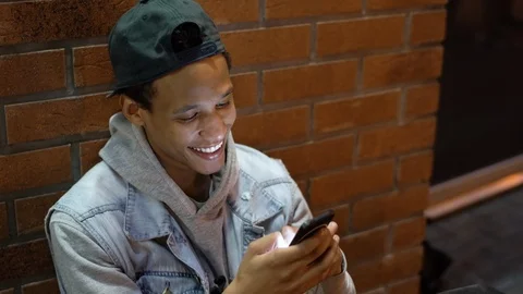 Multi-ethnic guy chatting and checking news feed of social network on his phone Stock Footage 115817564