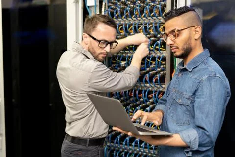 Multi-ethnic IT engineers setting up computer cluster Stock Photos