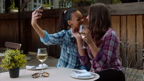 Multi-ethnic lesbian couple taking selfie picture with smart phone, while on lat Stock Footage 199632701