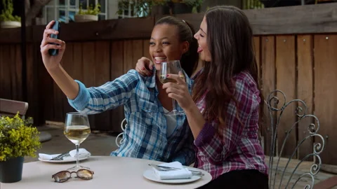 Multi-ethnic lesbian couple taking selfie picture with smart phone, while on lat Видео 199633102