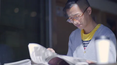Multi Ethnic Man Flips Through Newspaper At Local Coffee Shop Stock-Footage 56874488
