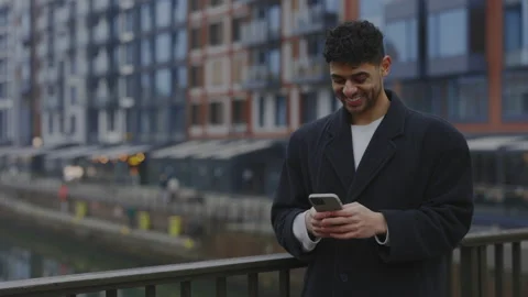 Multi ethnic Man standing holding his Smartphone Using Texting with Clients Stock Footage 233299656
