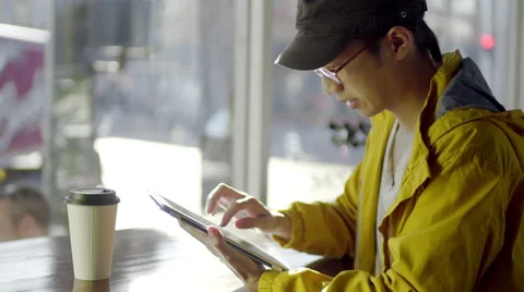 Multi-Ethnic Man Uses His Tablet At A Coffee Shop Видео 47128789