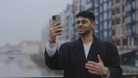 Multi ethnic man is video calling his friends standing outside. Male boss are Stock Footage 224494858