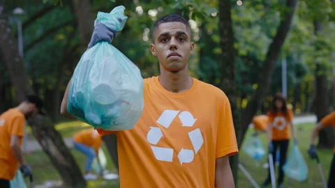 Multi Ethnic Man Wearing T-shirt with Recycling Symbol Holding Bag Full with Stock Footage 234868787