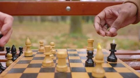 Multi-ethnic men playing chess in autumn park on a bench. Close-up. Stock Footage 271325643
