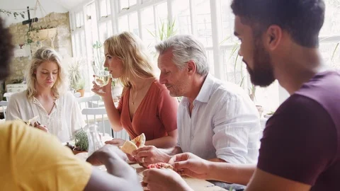 A multi ethnic, mixed age group of adult friends eating tapas together at a Stock Footage 99753538