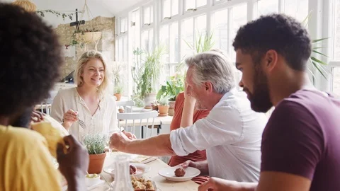 A multi ethnic, mixed age group of adult friends eating tapas together at a Stock Footage 99753560