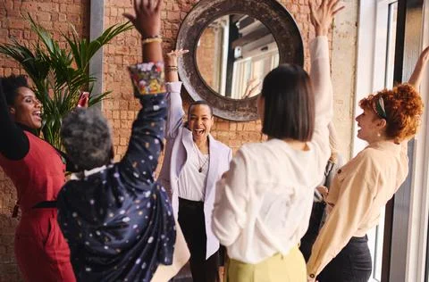 Multi ethnic mixed age range businesswomen cheering in support of Internation Stock Photos