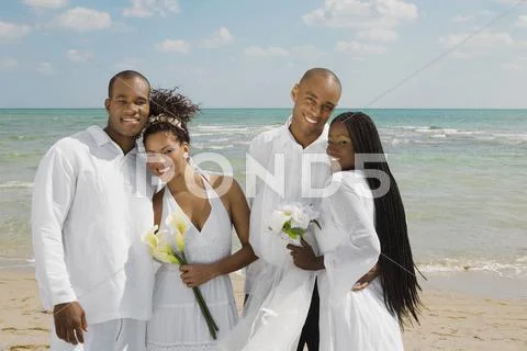 Multi-ethnic newlyweds hugging at beach Stock Photos