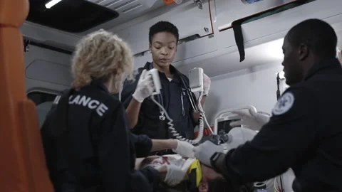 Multi ethnic paramedic saving life of man with defibrillator Stock Footage 163958376