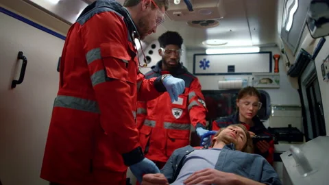 Multi ethnic paramedics checking man pulse on stretchers in emergency car Stock Footage 166903459