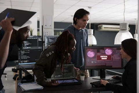 Multi ethnic programmers having security breach alert on computer screen 写真素材