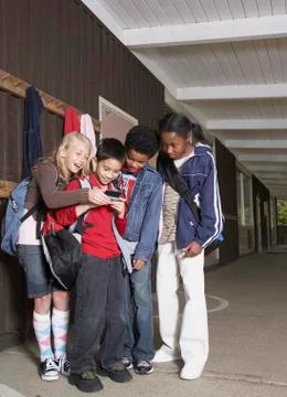 Multi-ethnic school children looking at cell phone Stock Photos