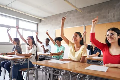 Multi-ethnic students in the classroom with hands raised. Smiling young people Stock Photos