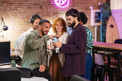 Multi ethnic team collaborating on project using mobile phone in modern office Stock Photos