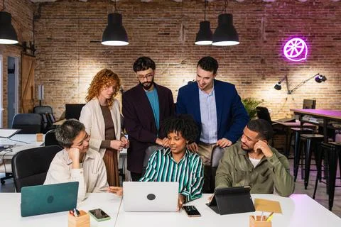 Multi ethnic team collaborating on project using laptop in modern office Stock Photos
