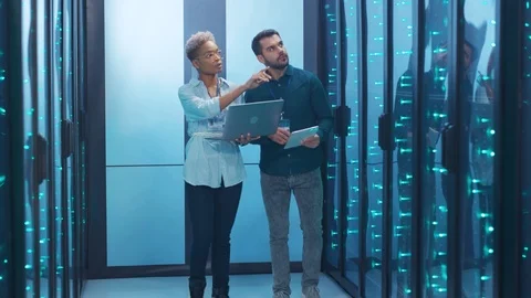 Multi-ethnic team of database specialists inspecting operative rack servers Stock Footage 119842134