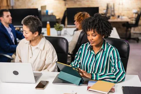 Multi ethnic team working together in modern office using digital tablet and Stock Photos