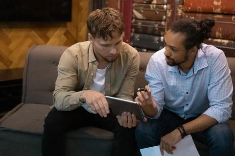 Multi ethnic teammates discussing collaborative project using digital tablet Stock Photos