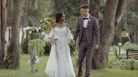 Multi ethnic wedding. The bride and groom walk holding hands. Happy newlyweds Video stock 156257168